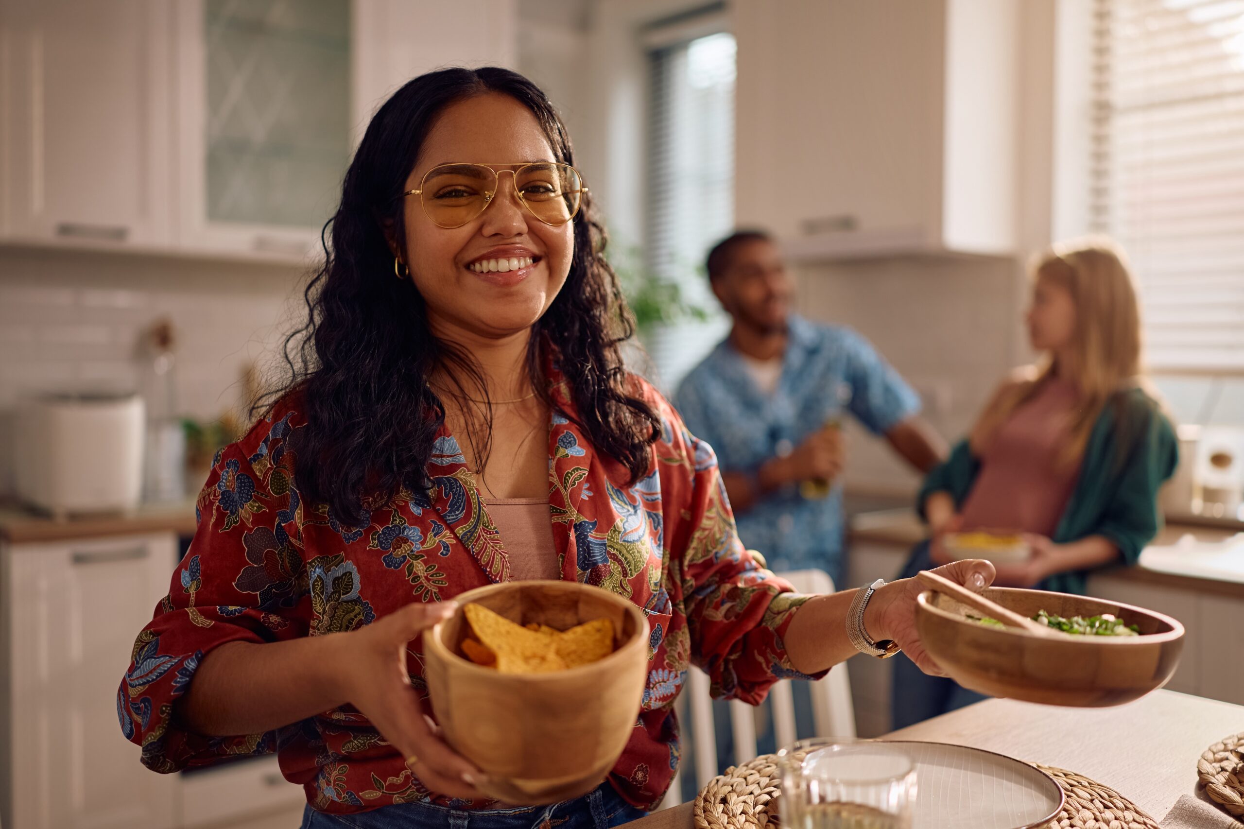 Young happy Indian woman having lunch party with her friends at home and looking at camera.